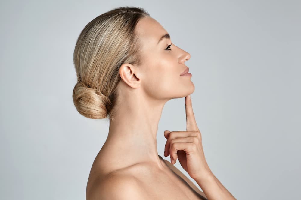 A woman highlighting her refined jawline results at Serenity Aesthetics & Wellness following non-invasive double chin treatment.