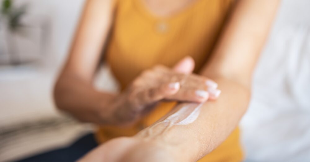Close up of a female hand applying a cream on her upper arm