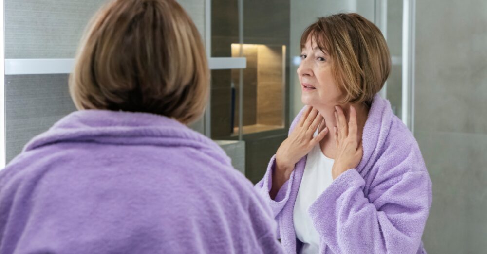 Woman in a purple robe looking at her reflection in the bathroom mirror