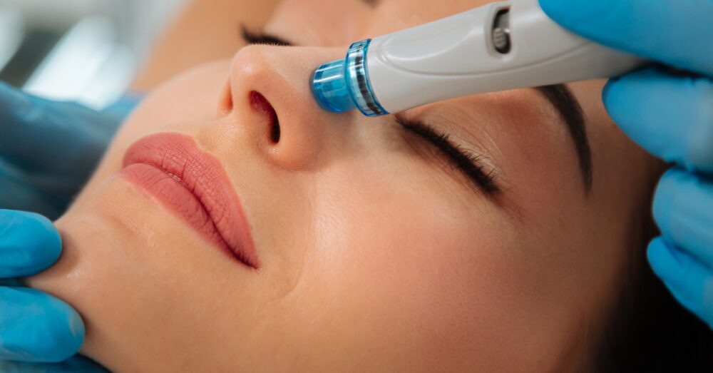 Provider using a HydraFacial device to deeply cleanse and hydrate a woman’s skin