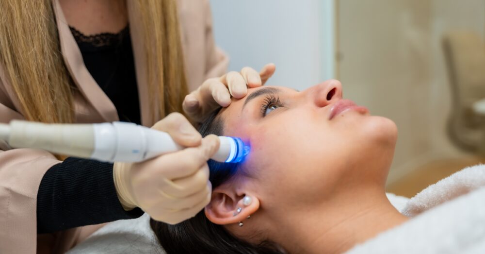 Aesthetician performing a HydraFacial treatment on a relaxed female