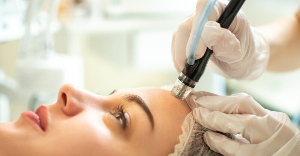 Close-up of a HydraFacial handpiece being used across a woman’s face