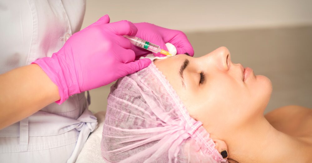 A provider administering a botox injection to the forehead area of a female in a clinical setting