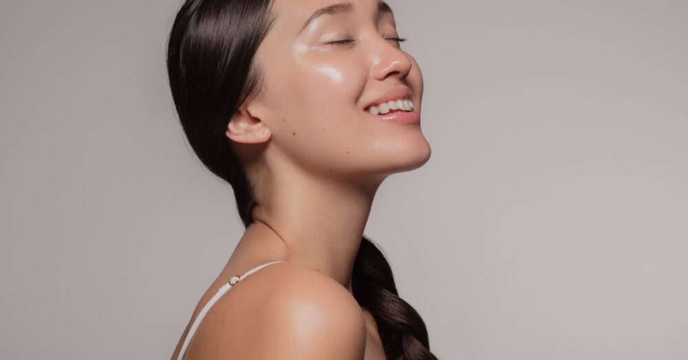 Woman smiling softly with her eyes closed against a neutral background
