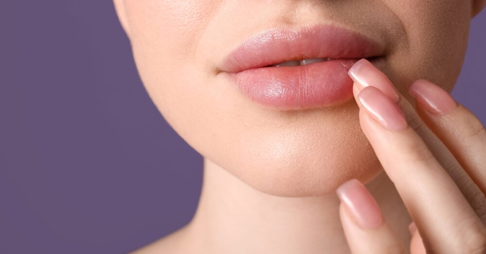 Close up image of a woman gently touching the side of her lower lip